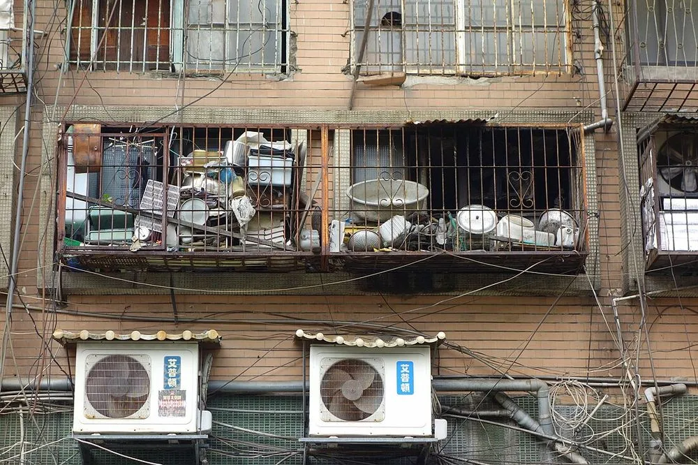 台北市大安路一棟舊公寓的外牆，鐵窗內側裝著兩台窗型冷氣，牆上另有管線與雜物。