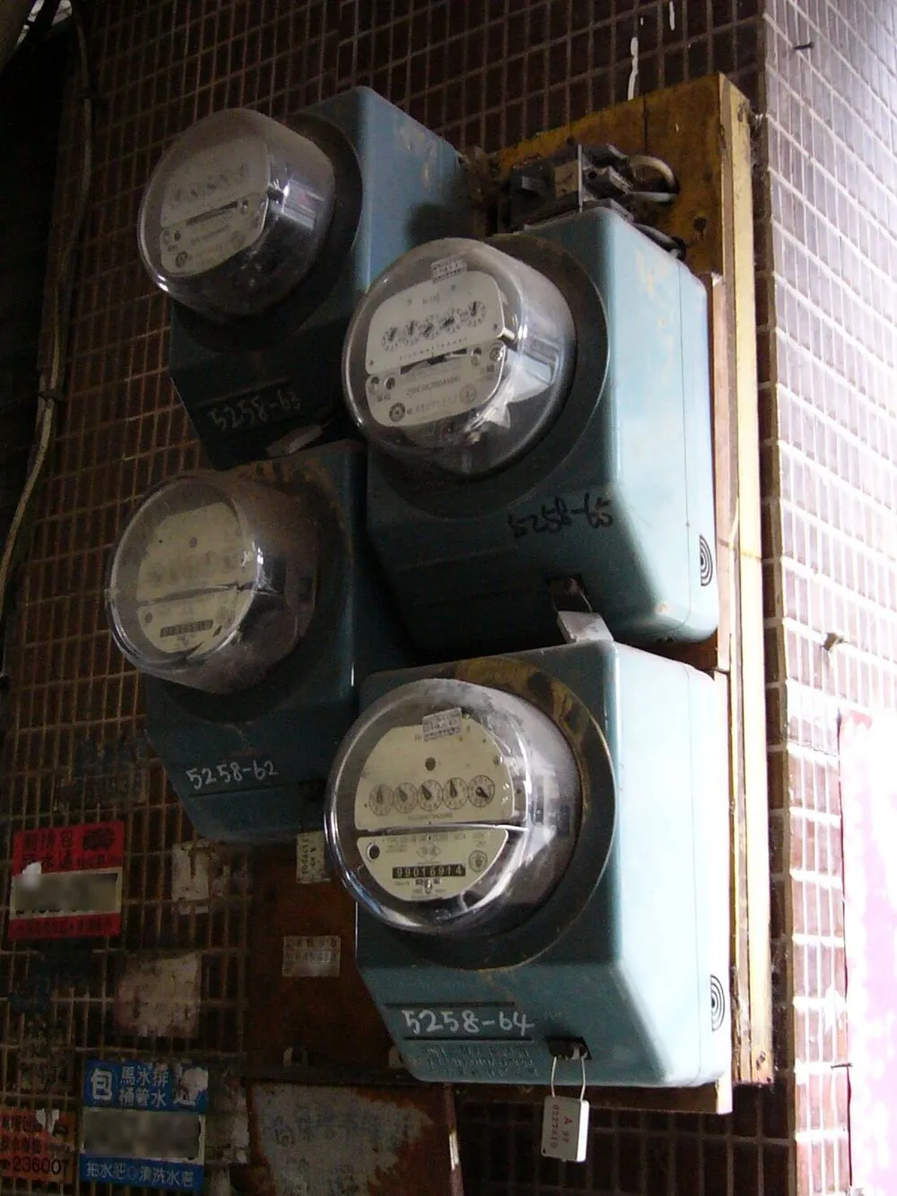 牆上並排的三具台灣電力公司機械式電表，各有手寫的表號。